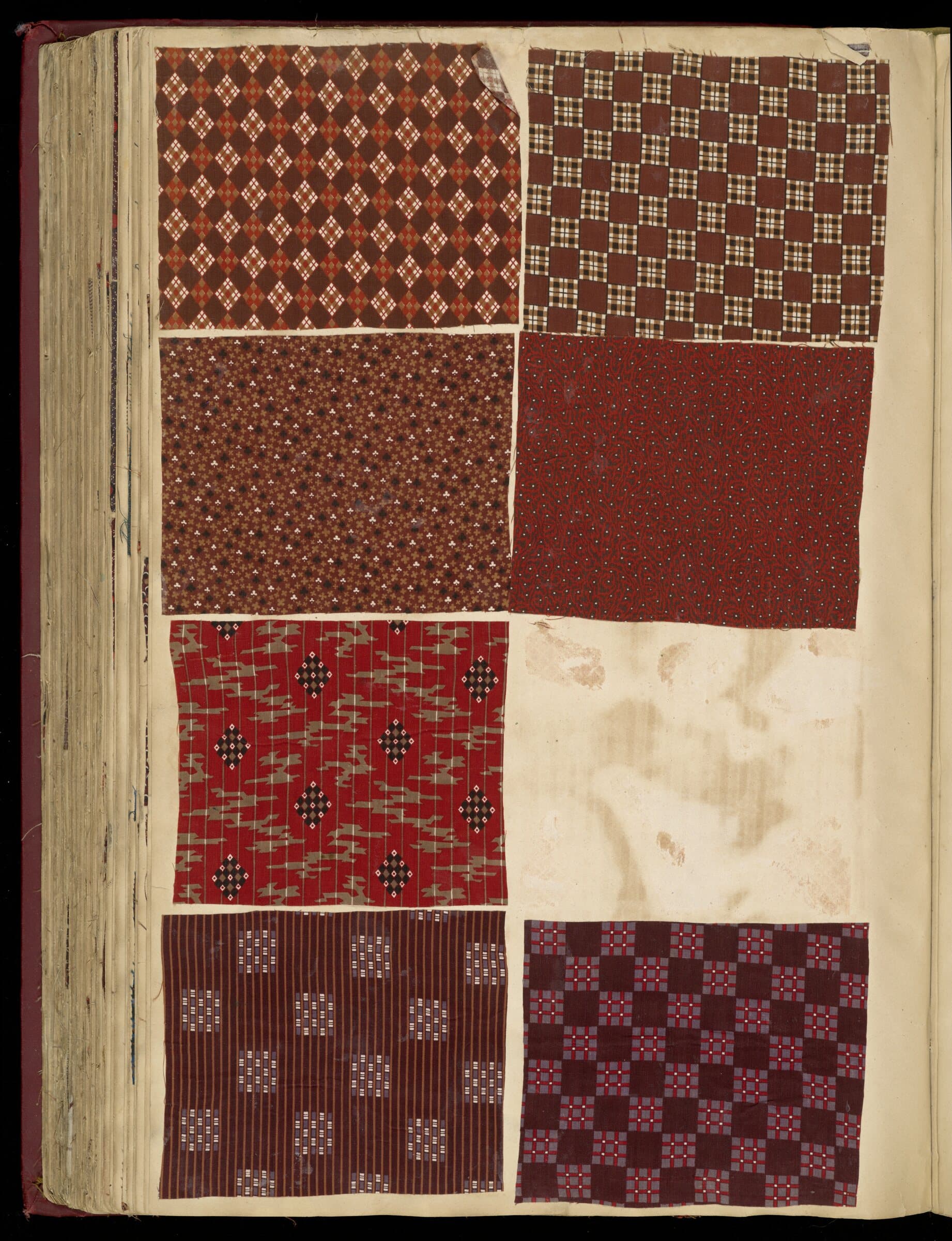 Page from a French fabric sample book of 1850, six printed cotton swatches in oxblood, brown and cream pinned to a parchment page.